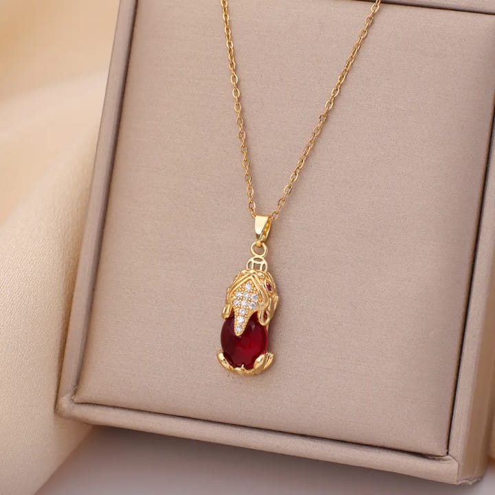 Elegant gold-plated pendant necklace with a teardrop red stone and crystal accents.