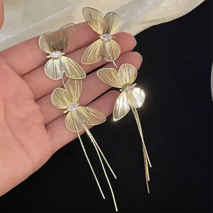 Elegant golden butterfly and clover earrings with crystal accents, showcasing nature-inspired design and artistic charm.