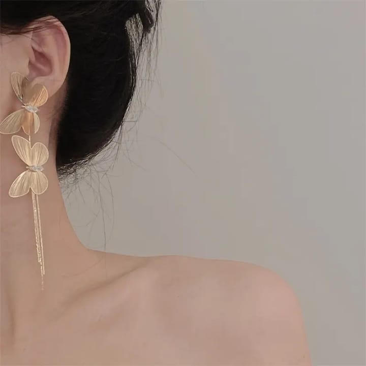 Elegant golden butterfly and clover statement earrings highlighting nature-inspired design and crystal detail.