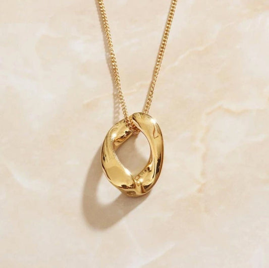 Bold minimalist twisted oval gold pendant necklace on a delicate chain, showcasing a glossy finish and unique sculpted design.
